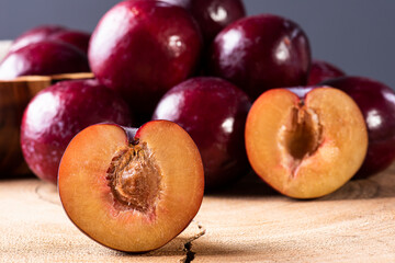 .Plum cut in half with some plums in the background. Wood background