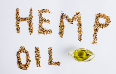 Hemp oil in a glass bowl and hemp seeds on white background.