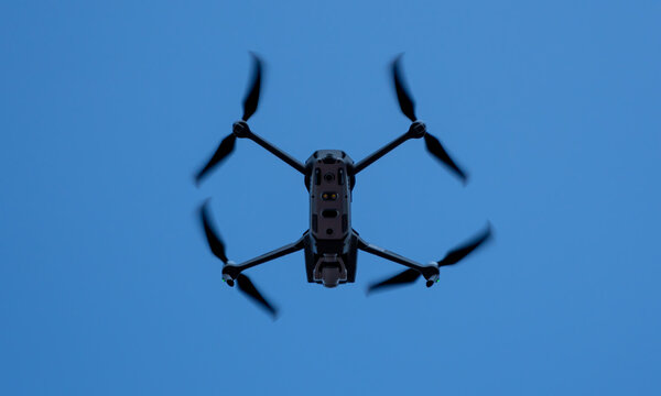 matt black generic drone flying free in the blue sky