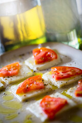 Tomato Slices on Squares of Buffalo Mozzarella Cheese drizzled in Oil in Sunlight