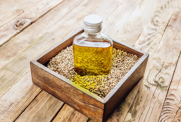 Hemp oil In a glass bottle and hemp seeds on rustic wooden background.