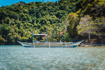 Boat on water surface in El Nido bay with jungle in background, Palawan, Philippines