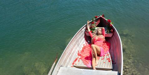 woman with long blond hair on boat on a blue lake