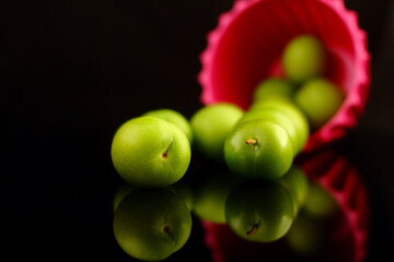 Green plums on black background