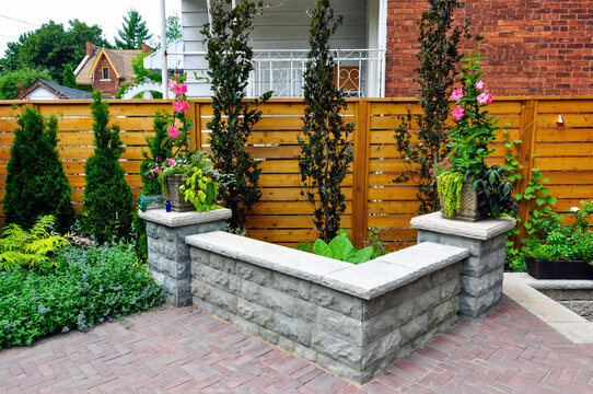 A retaining wall with natural stone coping and pillars added additional seating for entertaining in this small urban backyard garden.
