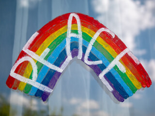 Painting of LGBT (Lesbian, Gay, Bisexual and Transgender) rainbow flag on window with the word Peace. Beautiful reflections of clouds in the glass