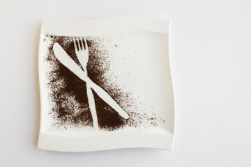 Printed knife and fork with cocoa powder in white plate with copy space.Top view
