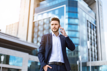 Attractive business executive speaking on cellphone in front of multistorey building