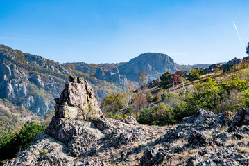Dynamic mountain landscape with bare rocks, green grass and distant high peak