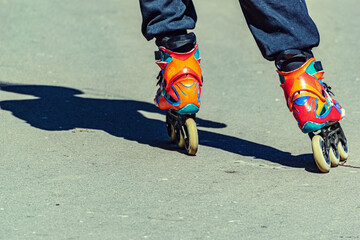 Close up of the legs of a guy riding a bright tricycle inline skates.