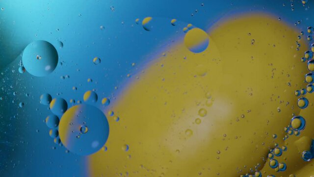 High quality abstract close-up 4k slow motion video of a bright colourful natural bacground with lemons and oranges giving orange blue and yellow colours with the water and oil bubbles moving around
