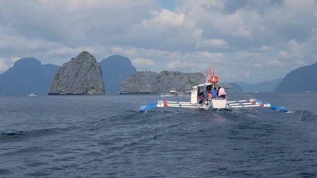 White catamaran floats on the sea among rocks in Philippines