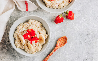 Quinoa porridge with coconut milk and fresh strawberries on light gray background. Healthy Lactose and Gluten Free Breakfast.