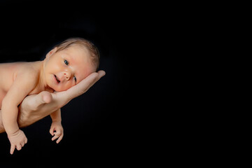 Father holding his 15 days old son in his hand on black background
