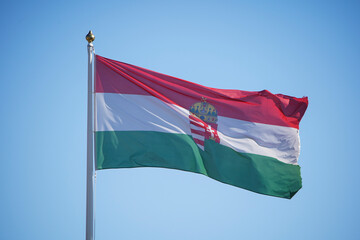 Hungary national flag waving in the wind with blue sky background. The flag of the Republic of Hungary is flying. Europe Hungary