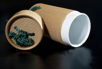 Cylindrical paper box for packaging on a black background.