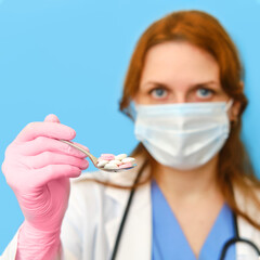 Doctor woman with a spoon full of pills on a blue background