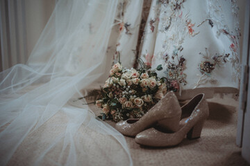 Bride's shoes, dress, veil and flowers close up