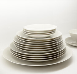 Stack of plates with different sizes in off white color against an off-white background.