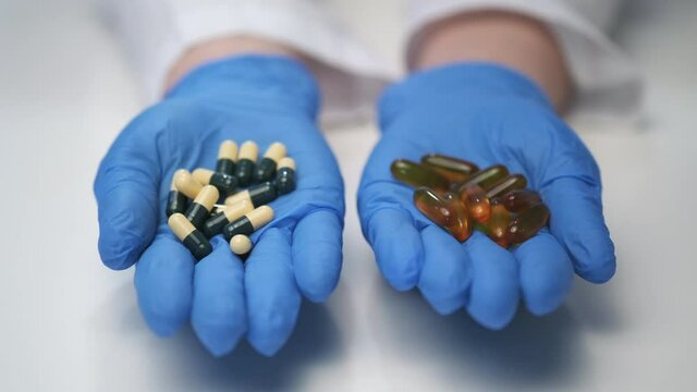 Many different pills in the hands of the doctor. A handful of drugs. Vitamins vs. pills. Concept.