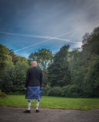 Man stands with Scottish flag kilt and image of Saltire in clouds