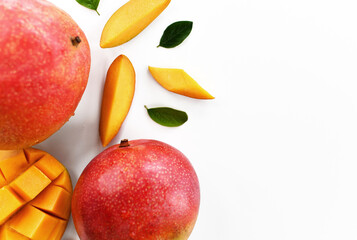 Slices and half of Mango fruit decorated with green leaves on white table background closeup Top view with free text copy space