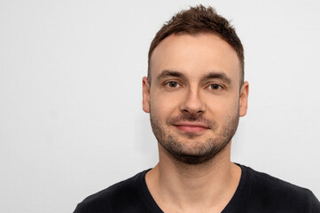 Fototapeta premium Portrait of a handsome man with unshaven stubble and tousled hair on a white background in a barbershop