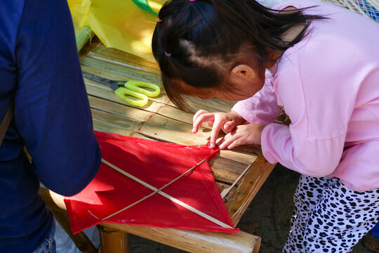 A cute little Asian girl is making a kite.