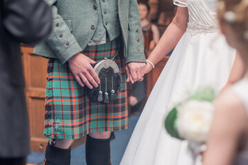Scottish wedding couple hold hands at ceremony with man in kilt - obrazy, fototapety, plakaty