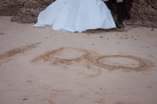 feet of bride and grrom on beach with I do written in the sand