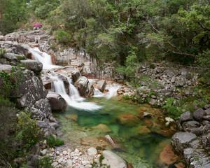Waterfall of Mata de Albergaria in the middle of the woods the water runs down the rocks until de green lake