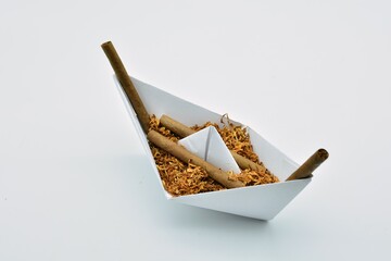 Barco de papel cargado de tabaco y puros habanos  sobre fondo blanco	