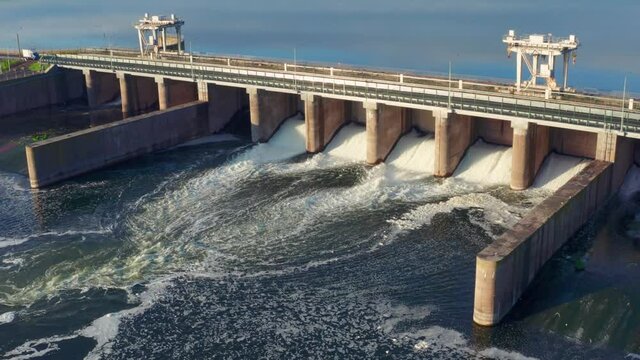 Hydroelectric dam or hydro power station at water reservoir, aerial view from drone. Draining water through gate, hydropower