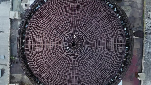 Take-off above round iron roof of unfinished nuclear power plant, round metal construction, industrial building, aerial top view