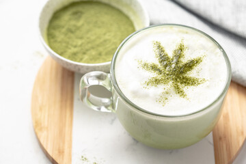 CBD or THC infused Matcha tea on white marble. Cannabis leaf tea. Warm vibes and relaxation. Healthy alternative to smoking or vaping. Medical or recreational use.