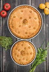 Two sweet potato pies with edible decorations on top - greens and tomatoes on the sides