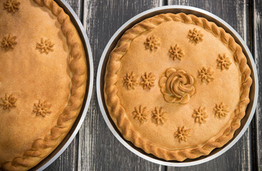 Two sweet potato pies with edible decorations on top standing on the wooden table