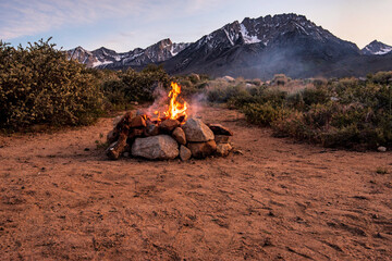 campfire in stone fire pit in desert at base of mountains with sunset sky - 355055905