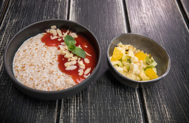 Delicious porridge with fresh fruits on separate bowl