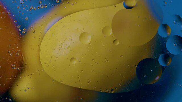 High quality abstract close-up 4k slow motion video of a bright colourful natural bacground with lemons and oranges giving orange blue and yellow colours with the water and oil bubbles moving around