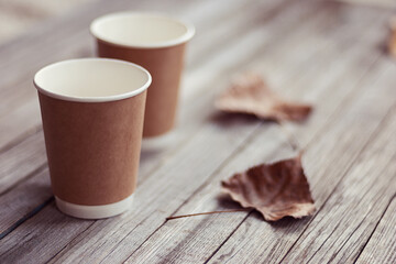 two paper cups standing on wooden table in outdoors cafe