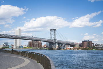 An empty promenade along East River in lower Manhattan with a view of Williamsburg Bridge