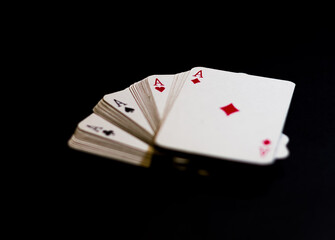 Obraz premium Ángulo levemente elevado de cuatro ases de poker aislados con luz selectiva sobre un fondo negro 