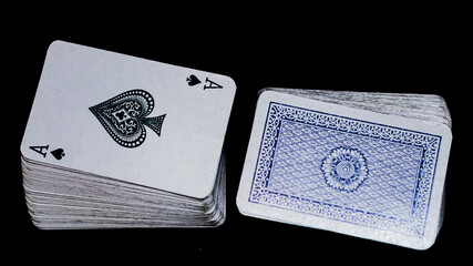 Primer plano de un as de espadas junto a un mazo de cartas azul con luz selectiva sobre un fondo negro