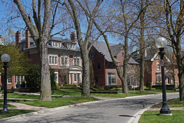 Street of large traditional detached homes with front yards and mature trees