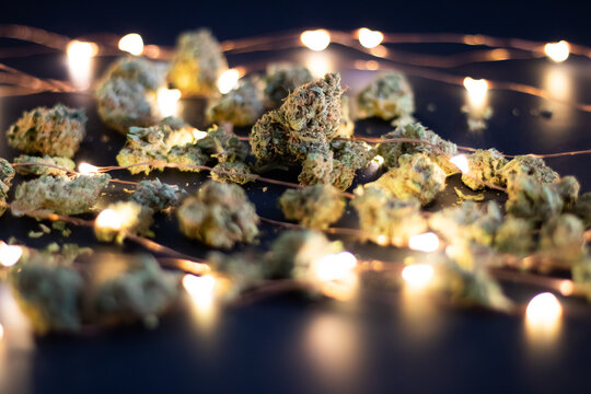 Close up of dried cannabis flower with twinkly lights on a dark background.