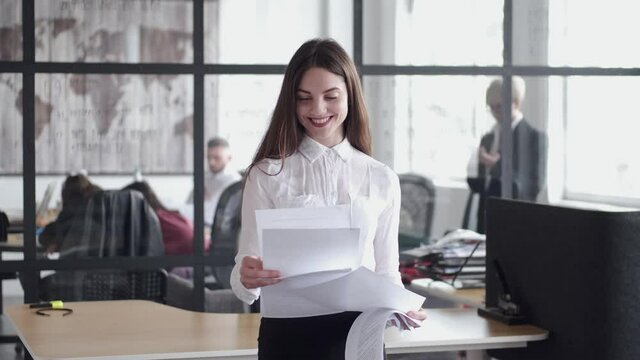Beautiful girl reading documents about business . She feels happy due to a well-concluded contract.