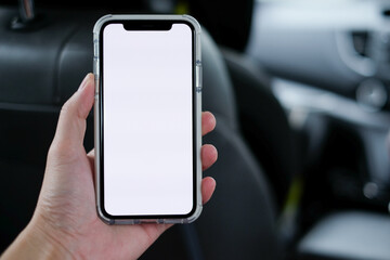 Close up view of man's hand holding smartphone with blank screen for copy space in car at passenger seat with blurred and defocused background.