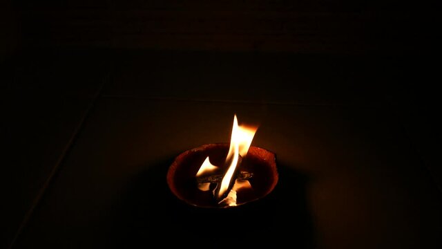 Spiritual flame natural candle burning on dark background Distanced View with Palo Santo wick for Smoke Clearing Energy Work Healing Aura in a Coconut Shell Beeswax Fuel Real Fire in 4k