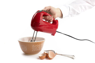 a cook using a red electric mixer with brown eggshells isolated on white